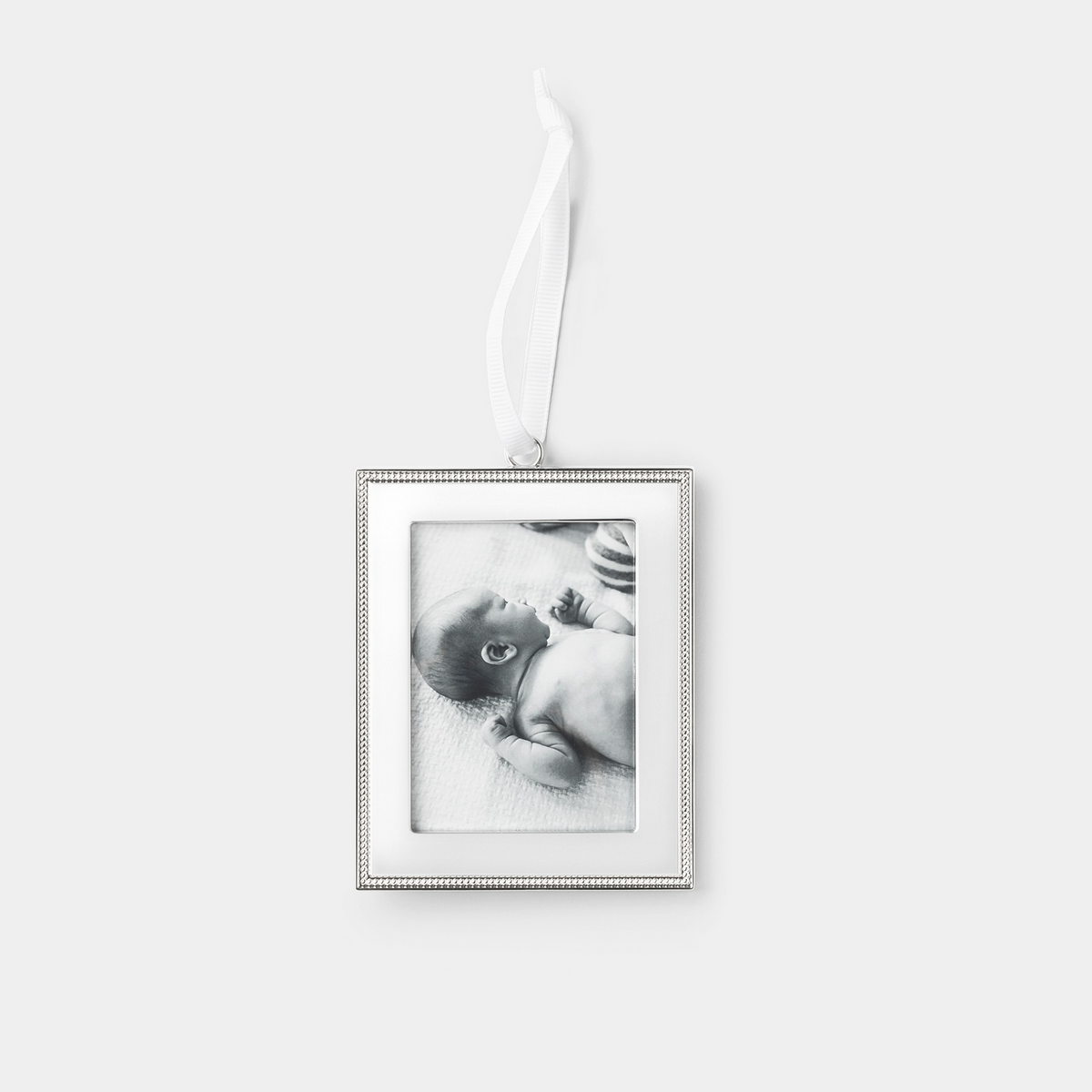 A rectangular silver picture frame ornament with a beaded border and a hanging white ribbon, shown against a light gray background. The photo insert inside the frame is a black-and-white image of a baby.